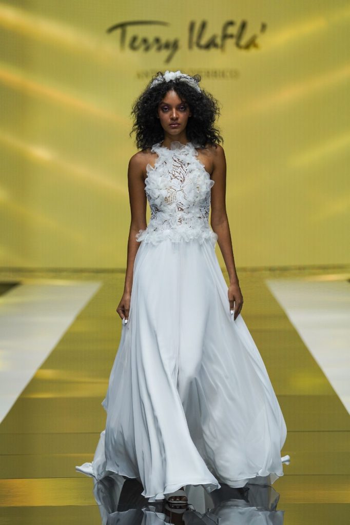 In questa foto la modella indossa un abito da sposa con scollo all'americana e fiori tridimensionali.