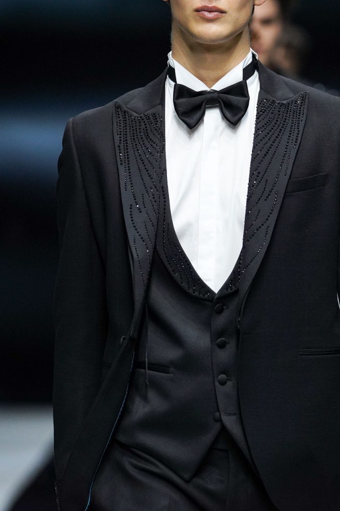 In questa foto il modello indossa un abito da sposo nero con dettagli luccicanti sul bavaro.