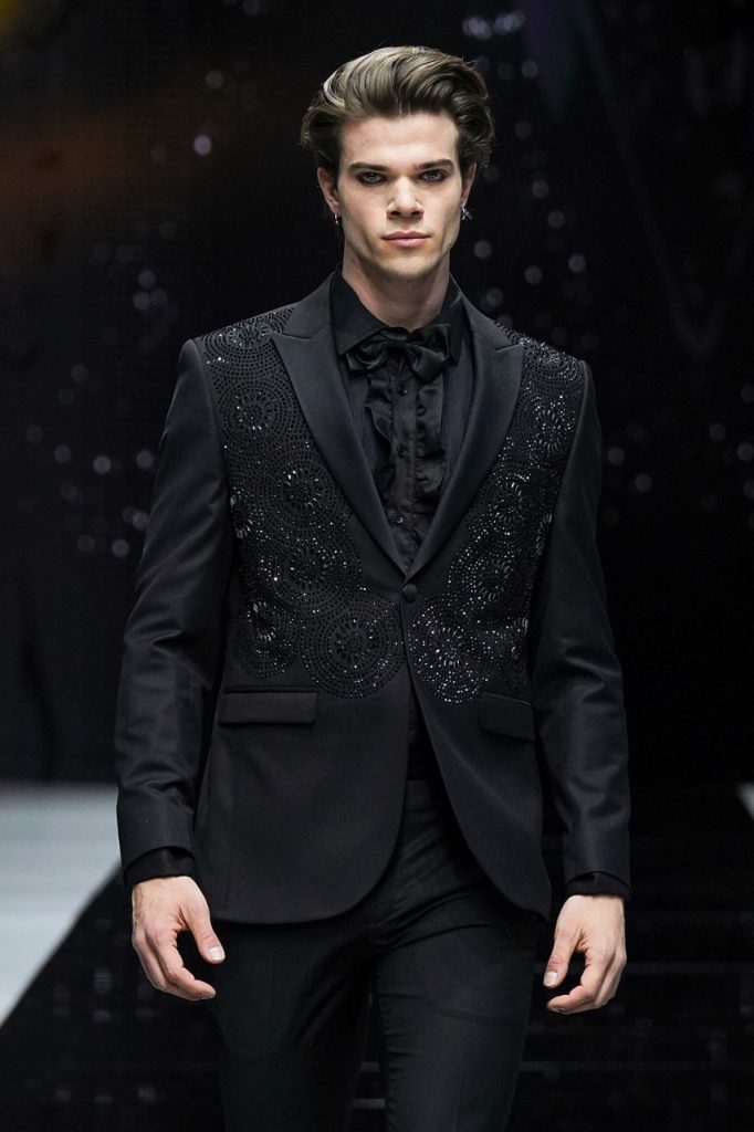 In questa foto il modello indossa un abito da sposo total black con dettagli lucccicanti.