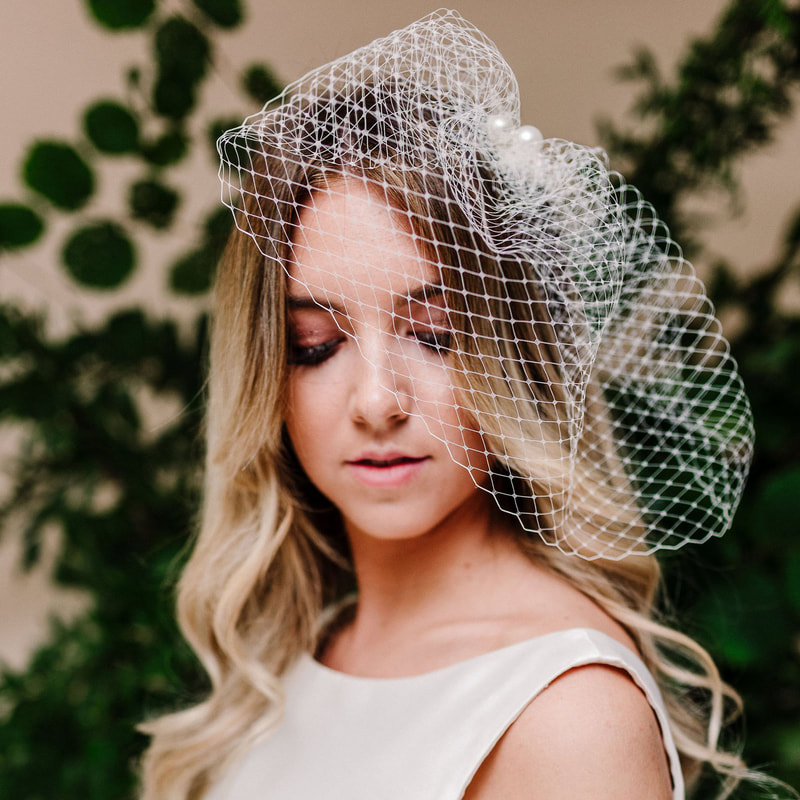 In questa foto una sposa con un fascinator a veletta, tra gli accessori da sposa per capelli vintage