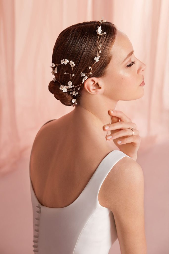 In questa foto una modella con uno chignon decorata da ramage floreale, tra gli accessori da sposa per capelli di Atelier Emè