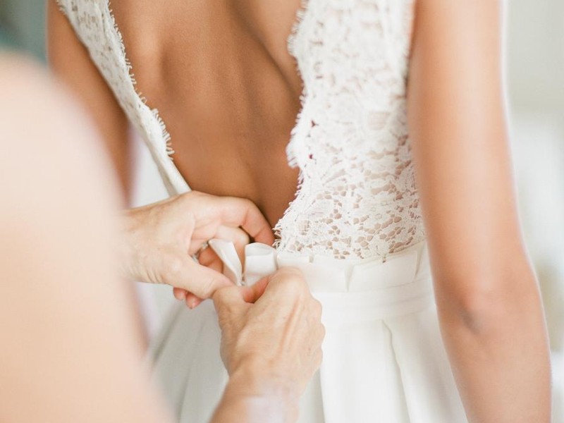 In questa foto durante la preparazione sposa le mani della mamma che chiudono l'abito della figlia sul retro