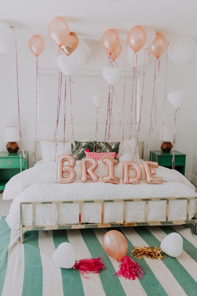In questa foto una camera da letto decorata per la preparazione sposa con i palloncini con la scritta bride colore oro rosa e palloncini al soffitto colore rosa e bianco
