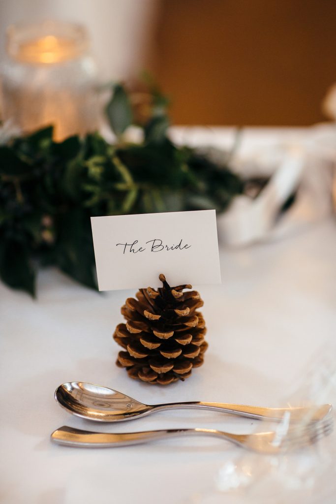 In questa foto una pigna con biglietto segnaposto colore bianco con scritto Bride