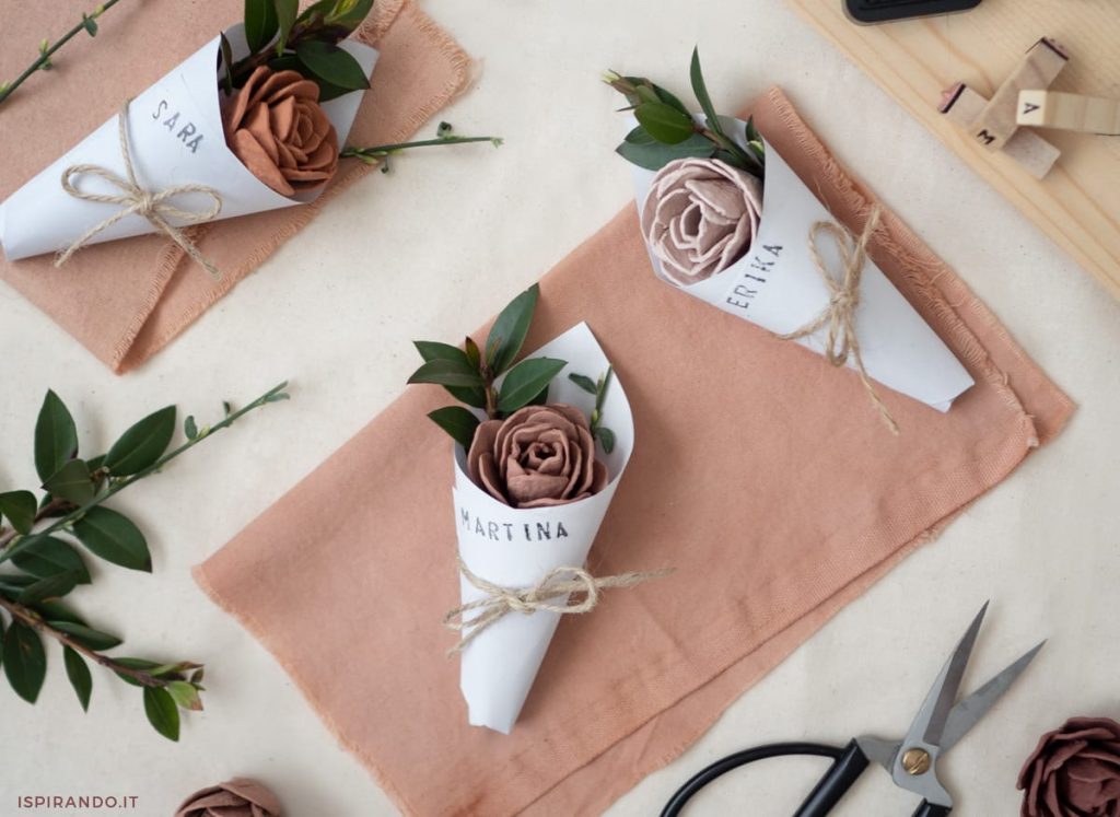 In questa foto segnaposto matrimonio con fiore in carta crepla nei toni del rosa e del mattone 