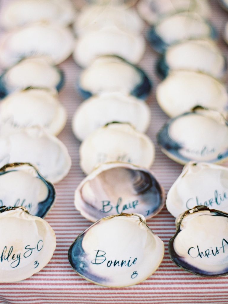 In questa foto conchiglie con nomi degli ospiti usati come segnaposto per matrimonio 