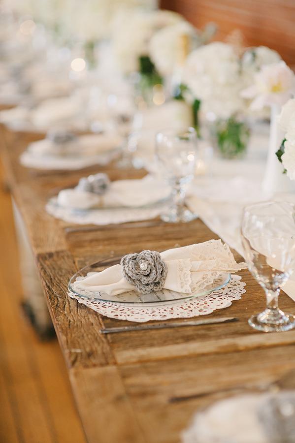 In questa foto un segnaposto di matrimonio all'uncinetto colore grigio a forma di fiore con perla al centro 