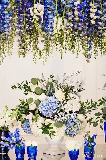 In questa foto, centrotavola e decorazioni floreali pensili realizzate con fiori bianchi e blu tra cui ortensie e delphinium