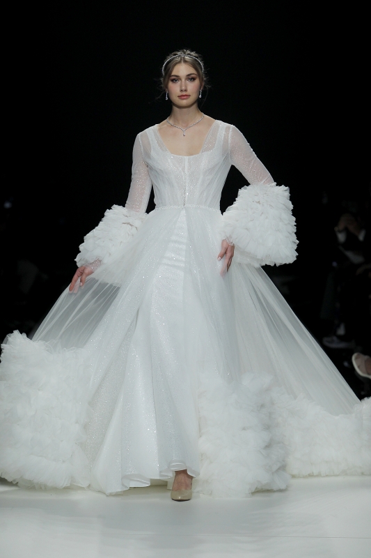 In questa foto la modella indossa un abito da sposa con vestaglia trasparente con balze di tulle.