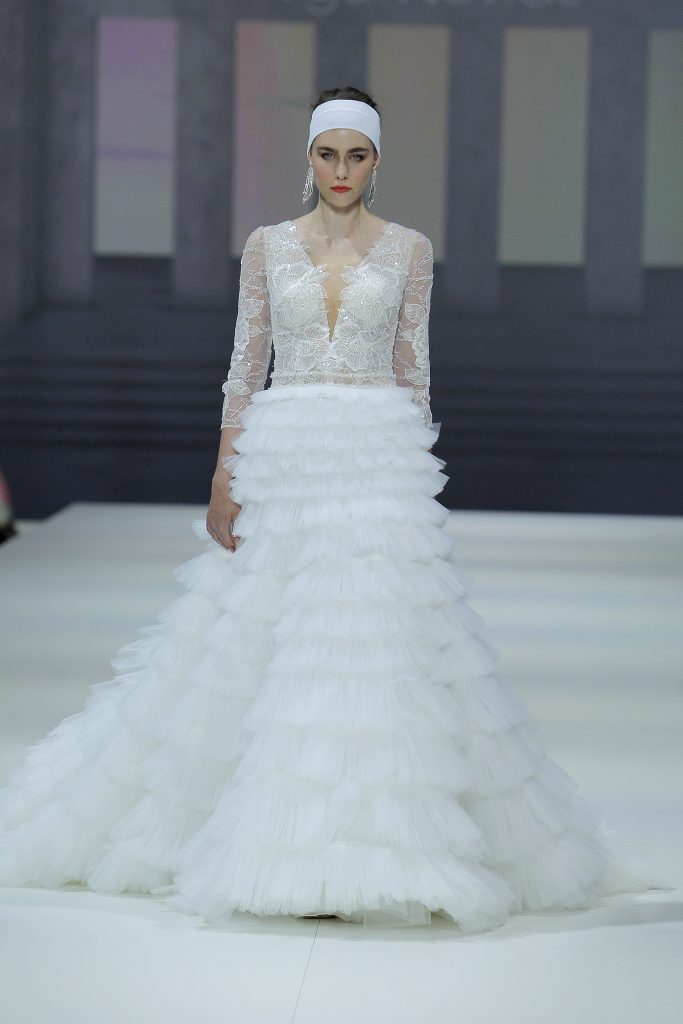In questa foto la modella indossa un abito da sposa con gonna con microbalze 2023.