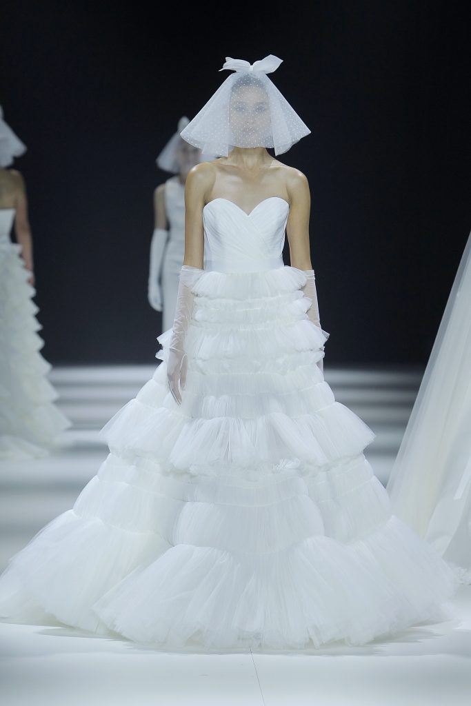 In questa foto la modella indossa un abito da sposa con gonna con microbalze 2023.