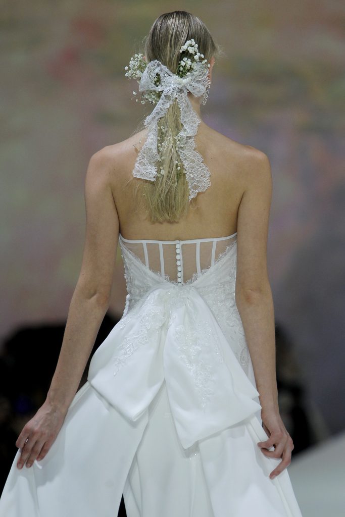 In questa foto la modella indossa un abito da sposa con maxi fiocco sul retro di Marchesa for Pronovias 2023.