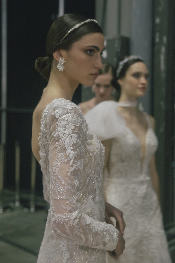 In questa foto la modella indossa un abito da sposa con maniche lunghe e pizzo floreale.