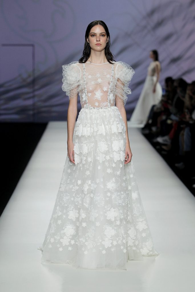 In questa foto la modella indossa un abito da sposa romantico 2023 con gonna di tulle trasparente e fiori 