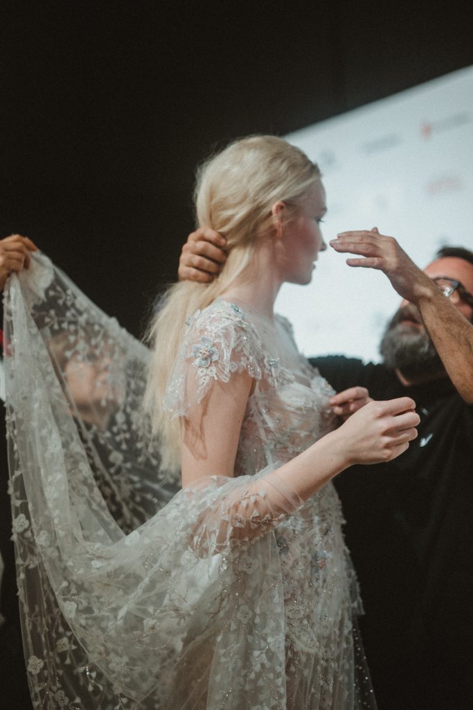 In questa foto la modella indossa un abito da sposa con pizzo e fiori 3D di Yolan Cris.