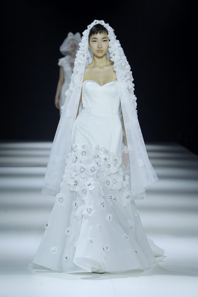 Inq uesta foto la modella indossa un abito da sposa con fiori 3D 2023 e fiori sul velo.