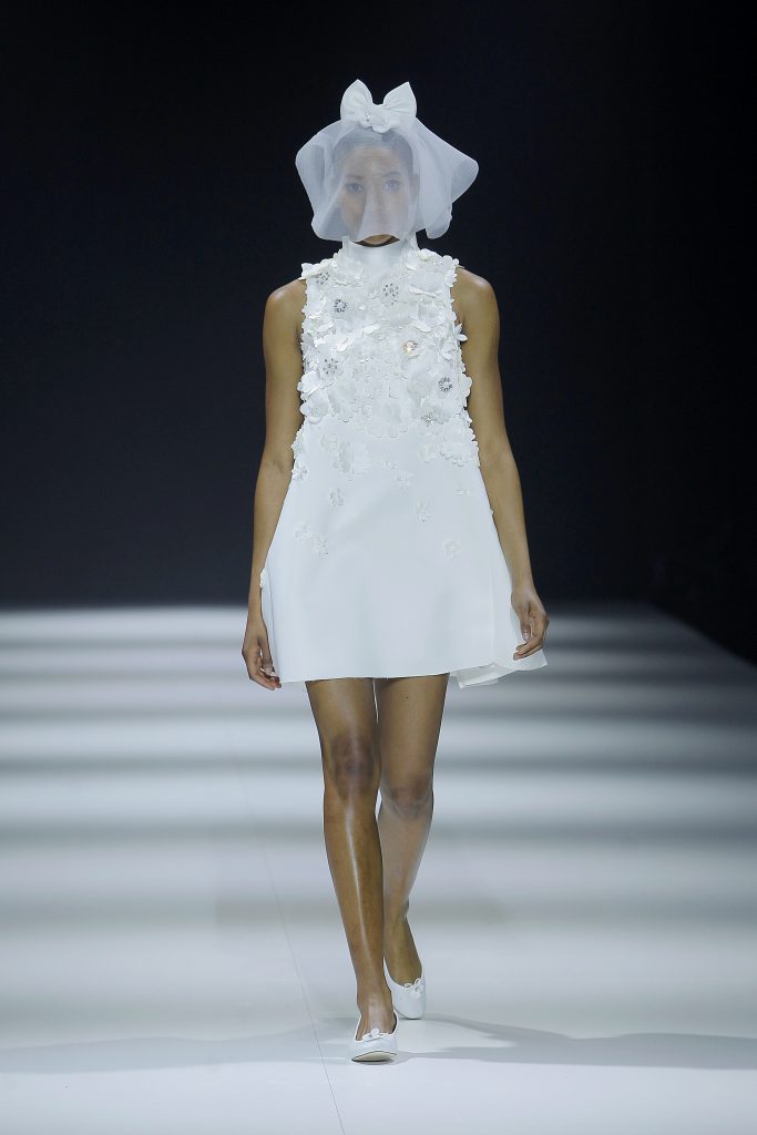In questa foto la modella indossa un abito da sposa corto 2023 con fiori 3D Viktor & Rolf.