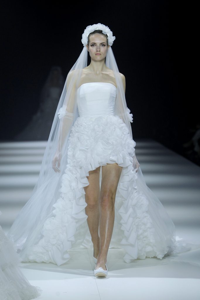 In questa foto la modella indossa un abito da sposa corto con coda di rouches.