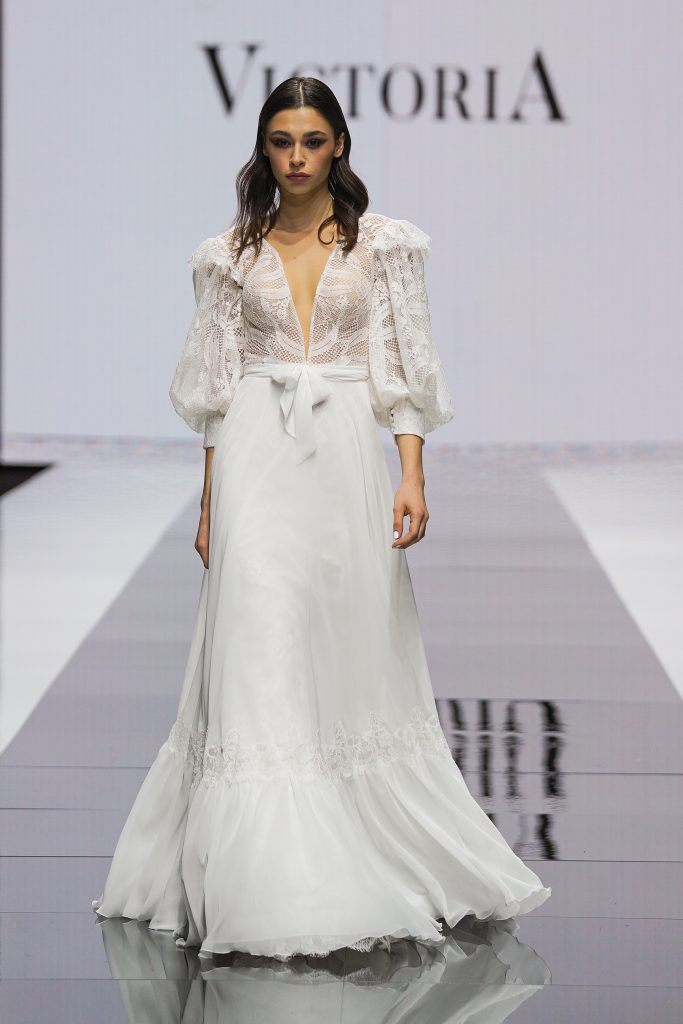 In questa foto la modella indossa un abito da sposa con scollo a V e fiocco in vita di Maison Signore 2023.