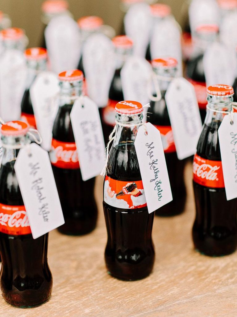 In questa foto escort card commestibili legate a piccole bottiglie di vetro di Coca Cola