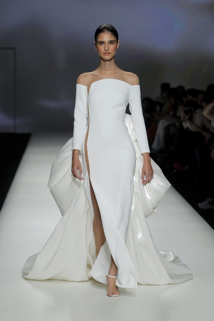 In questa foto la modella indossa un abito da sposa con spacco e maxi fiocco Isabel Sanchis 2023.