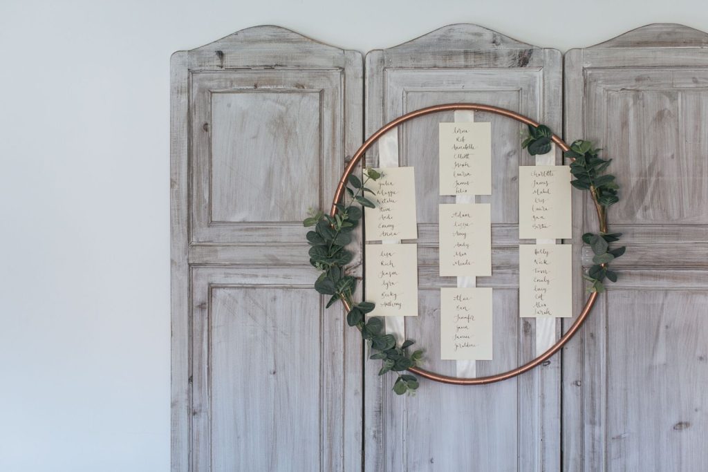 In questa foto un tableau di matrimonio a forma di cerchio attaccato su un separé di legno chiaro stile Shabby Chic