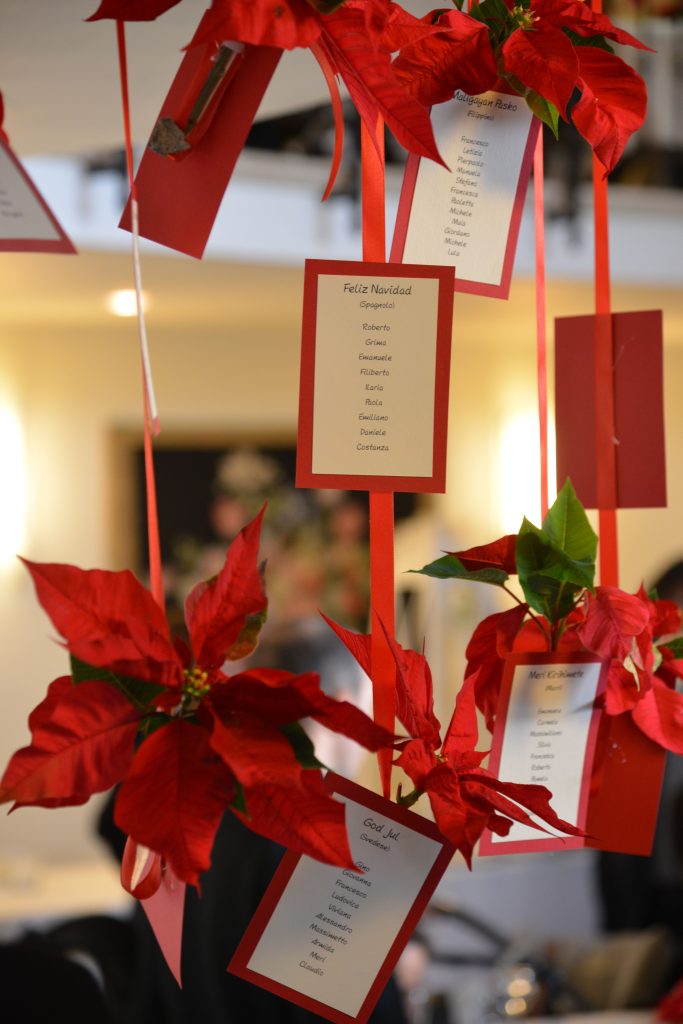 In questa foto un tableau de mariage a tema natalizio con bigliettini appesi e fiori di stelle di Natale