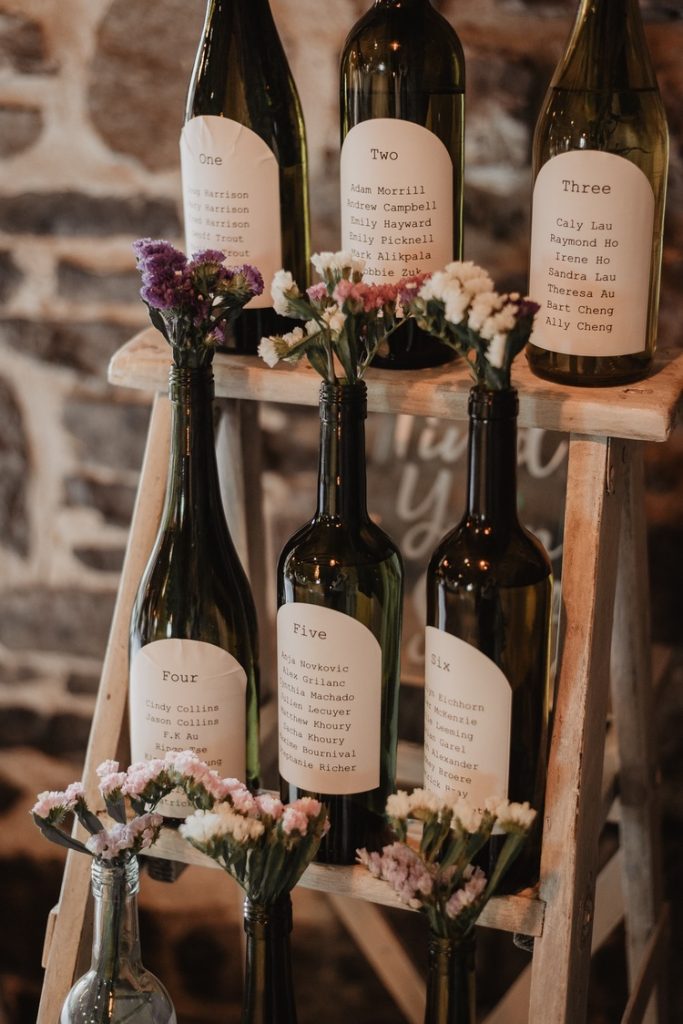 In questa foto un tableau matrimonio a tema con bottiglie decorate con fiori di campo
