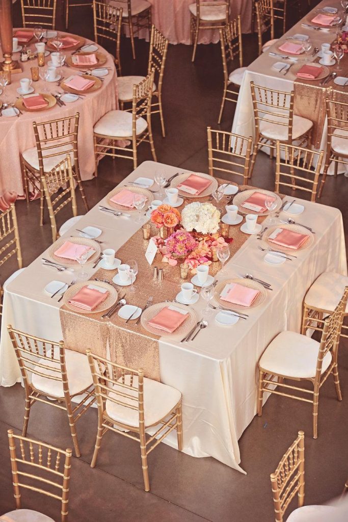 In questa foto tavoli di un un ricevimento di nozze visti dall'alto con allestimenti nei toni del rosa e dell'oro