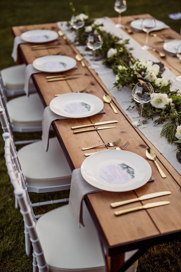 In questa foto un tavolo rettangolare per matrimonio con runner floreale e mise en place colore oro e lilla