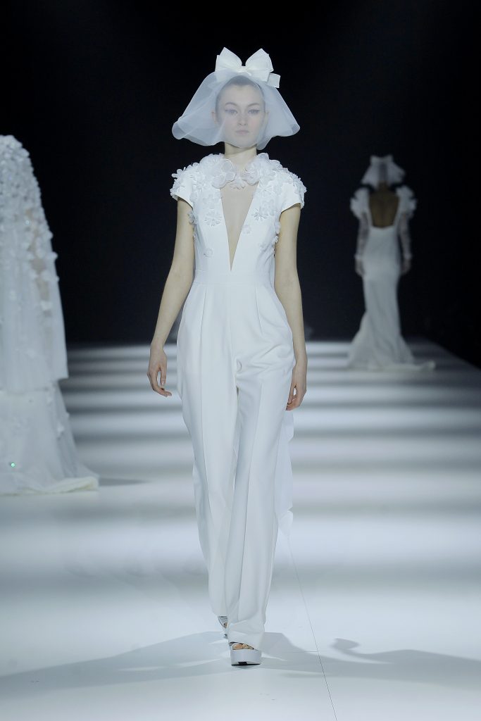 In questa foto la modella indossa un abito da sposa jumpsuit con scollo a V e fiori tridimensionali.