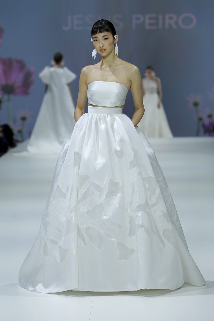 In questa foto la modella indossa un abito da sposa con top e gonna ampia con motivi floreali in contrasto.