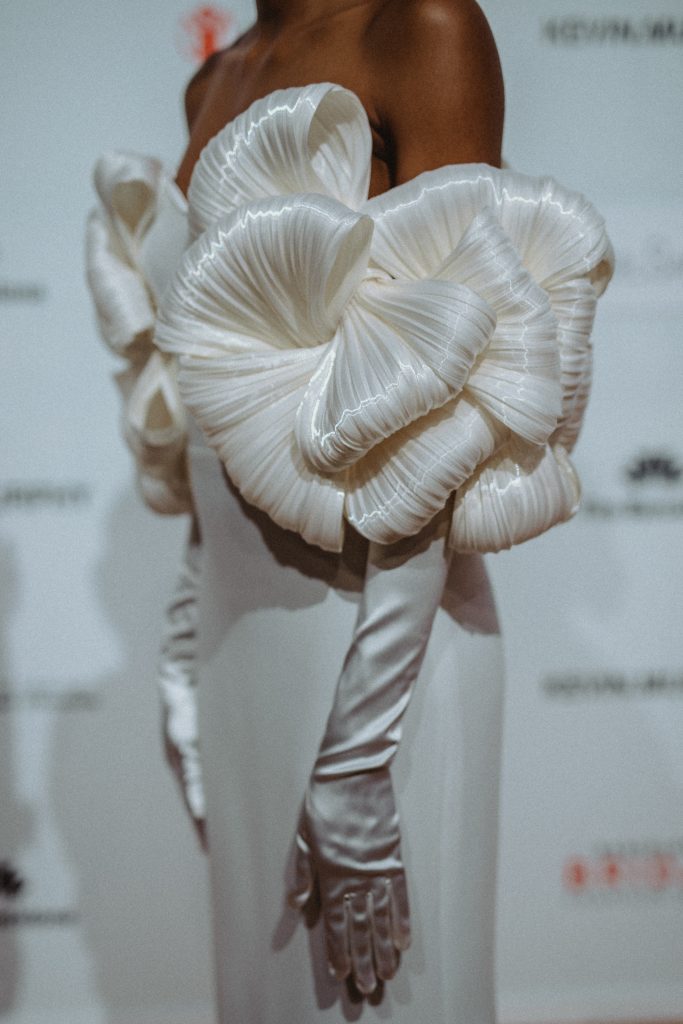 In questa foto la modella indossa un abito con maniche a scultura e guanti bianchi.