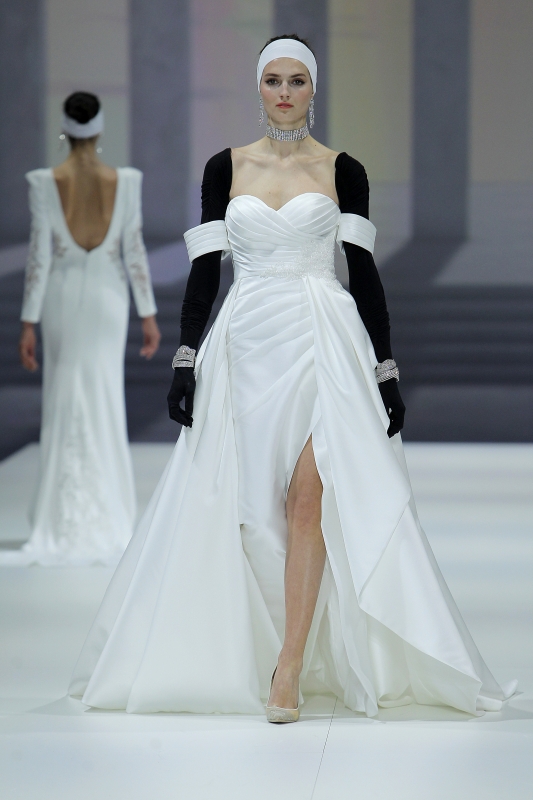In questa foto la modella indossa un abito da sposa bianco con maniche a guanto nere e spacco frontale.