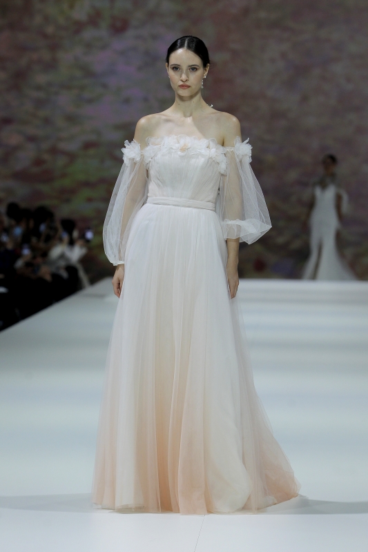 In questa foto la modella indossa un abito da sposa colorato 2023 con sfumatura pesca e maniche a sbuffo.