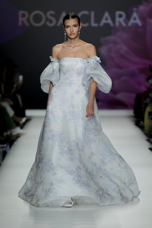 In questa foto la modella indossa un abito da sposa particolare 2023 con tessuto stampato con fiori celesti.