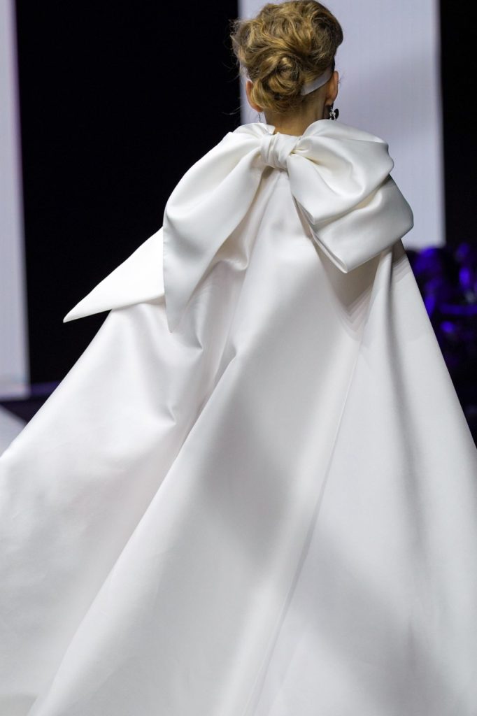 In questa foto la modella indossa un abito da sposa con cappa 2023 con maxi fiocco sul retro