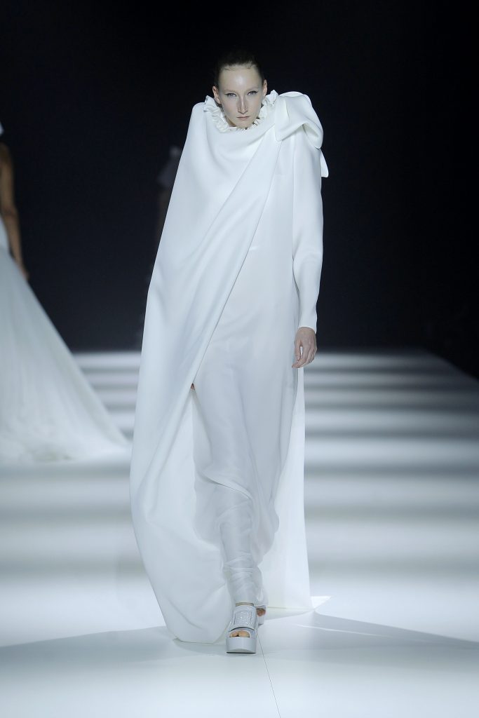 In questa foto la modella indossa un abito da sposa lungo con mantella.