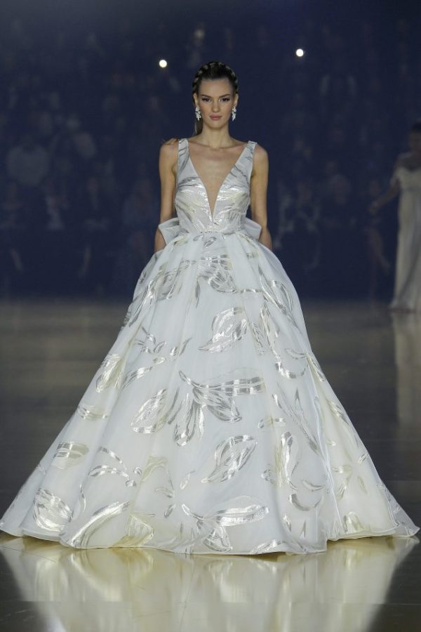 In questa foto la modella indossa un abito da sposa particolare 2023 Pronovias in organza stampata con motivi argentati-