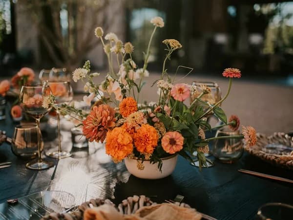 In questa foto, un centrotavola scomposto con i toni dell'arancione è protagonista di un matrimonio tema hippie