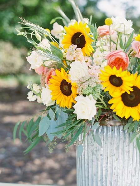 In questa foto, una composizione di fiori stile country realizzata con rose e girasoli