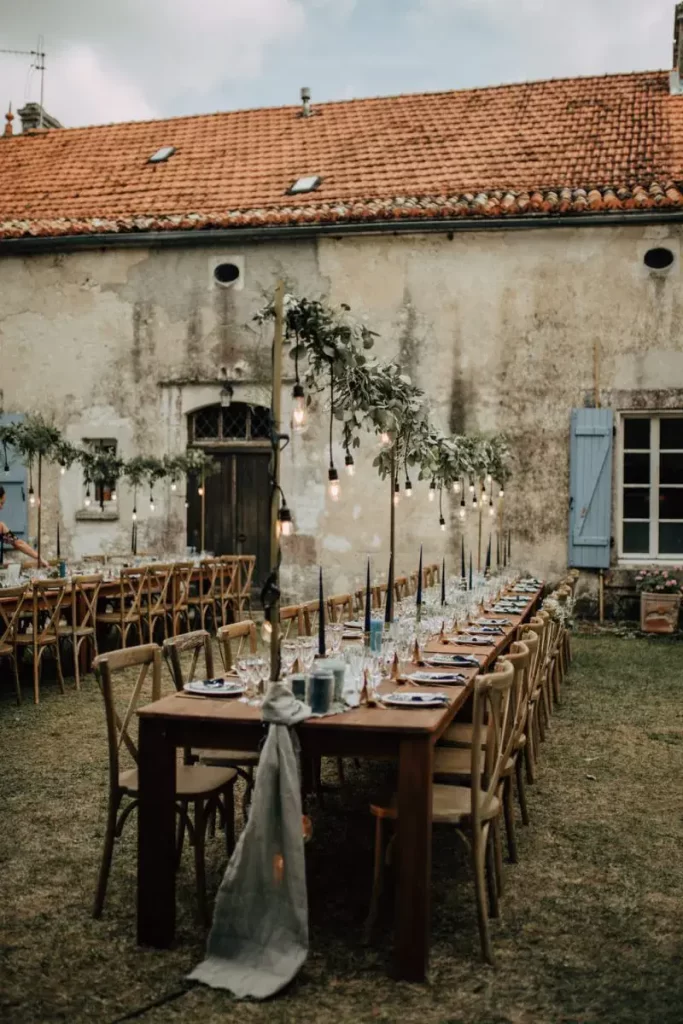 In questa foto un'idea di allestimento country chi in un antico casale. I tavoli sono imperiali e decorati con un runner colore azzurro, candele abbinate e luci sospese