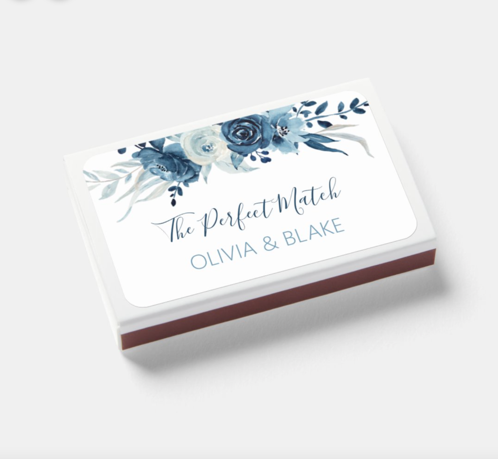 In questa foto un'idea di gadget per matrimonio: scatole di fiammiferi decorate con fiori blu e personalizzate con nomi degli sposi e data delle nozze