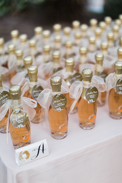 In questa foto un'idea di gadget per matrimonio: piccole bottiglie di spumante rosé con tag colore oro