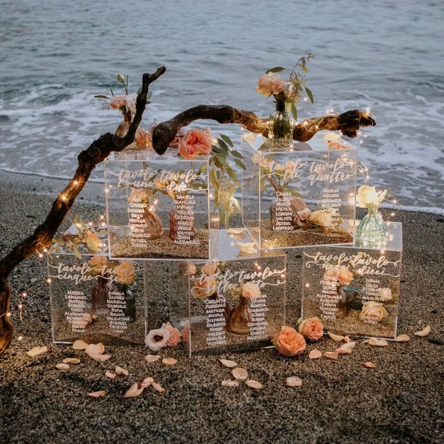 In questa foto un'idea di tableau mariage sulla spiaggia. I nomi degli ospiti sono incisi su lastre di plexiglass