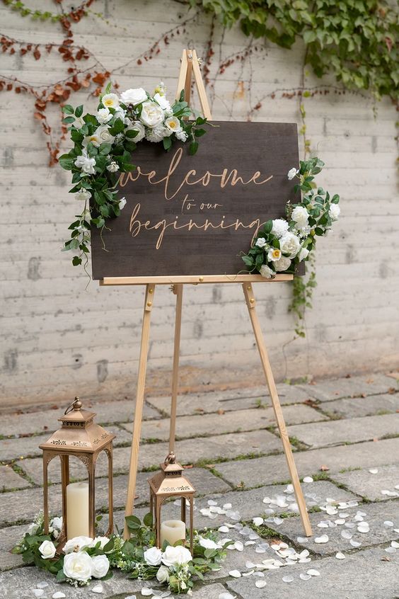 In questa foto l'idea di welcome board in legno decorata con fiori di colore bianco