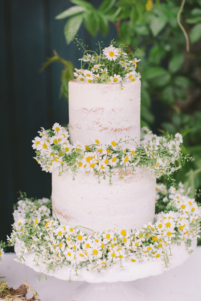 in questa foto una torta per matrimonio decorata con piccole margherite