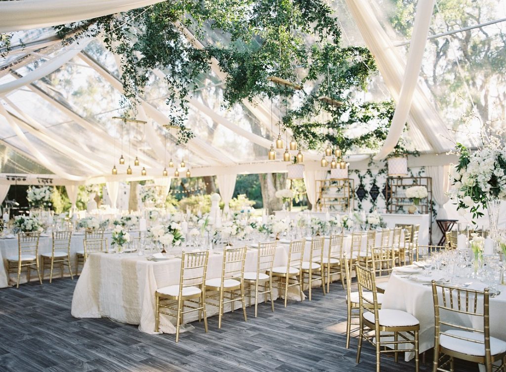 In questa foto un'idea di allestimento elegante nei toni del bianco e dell'oro in un ricevimento in una serra immersa in un giardino