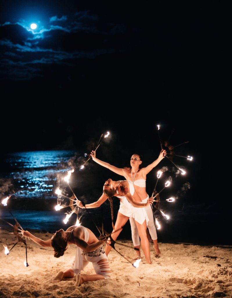 In questa foto idee per matrimonio intrattenimento: lo spettacolo di ballerine con il fuoco sulla spiaggia