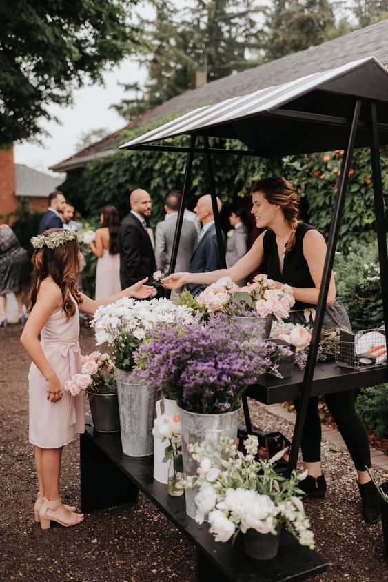 In questa foto idee per matrimonio intrattenimento: il Flower Bar in cui una fiorista professionista insegna ad un'ospite a creare un piccolo bouquet con fiori a tema